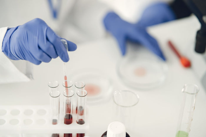 Persona con guantes usando una pipeta para dosificar muestra líquida en tubos de ensayo