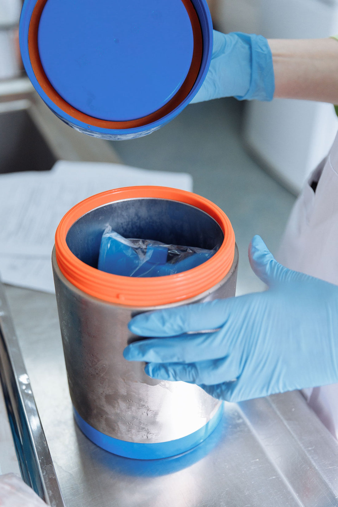 Científico con guantes manipulando un contenedor de conservación en frío de muestras en el laboratorio